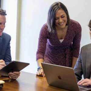 Workers gathered around a laptop in a conference room